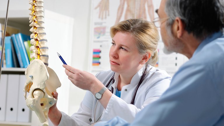 Médica a explicar ao doente as possíveis complicações de doenças ósseas metabólicas decorrentes da doença renal crónica