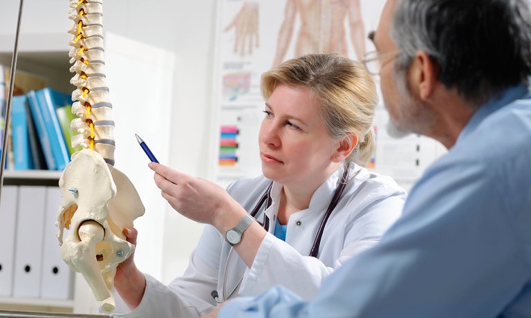 Médica a explicar ao doente as possíveis complicações de doenças ósseas metabólicas decorrentes da doença renal crónica